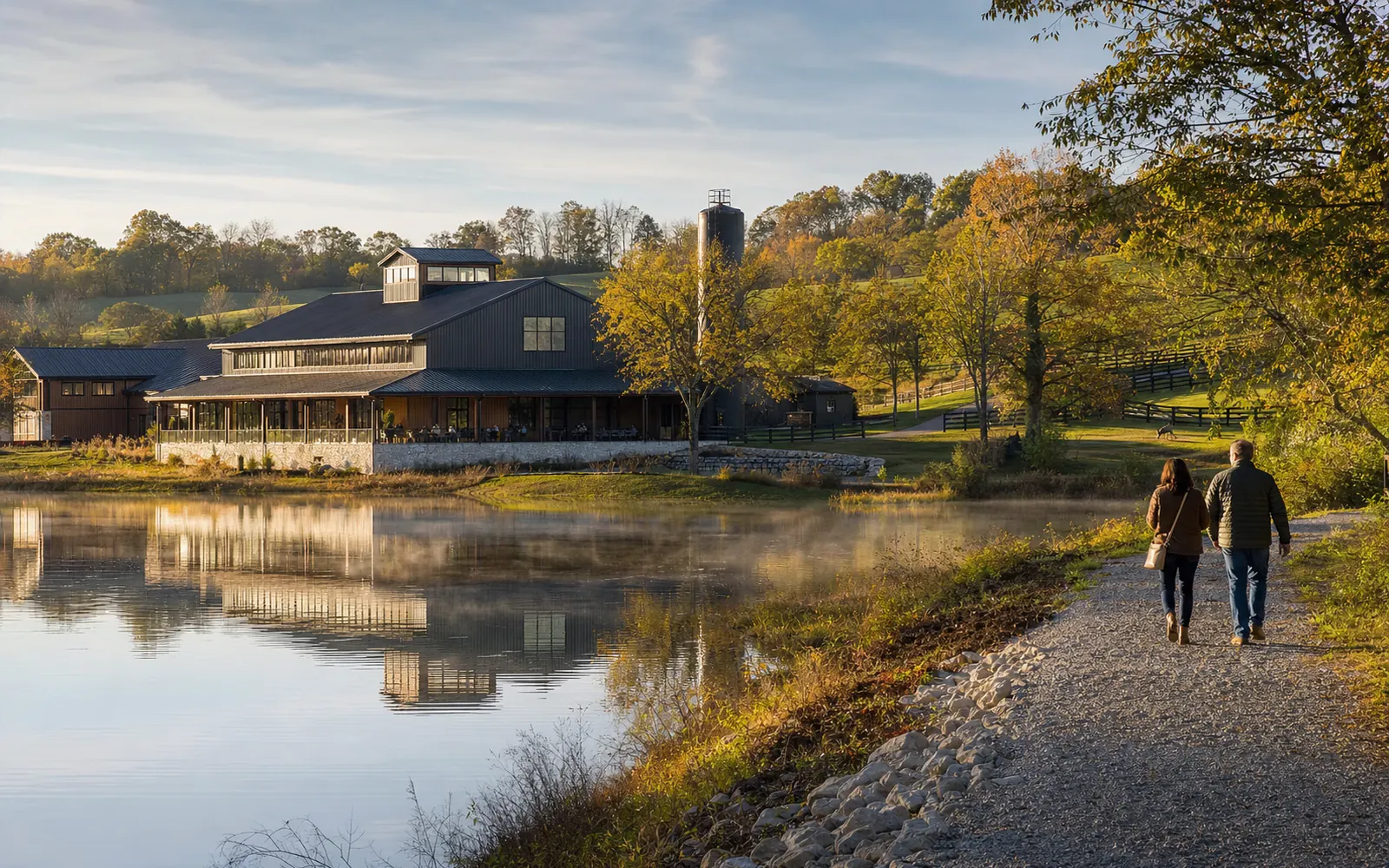 A rustic distillery tasting building beside a small lake at golden hour, with a couple walking the lakeside path, AI-generated illustration