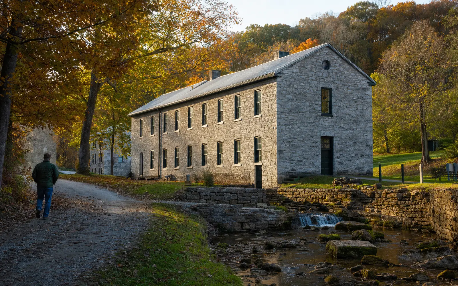 Old limestone distillery building among autumn trees at the bottom of a wooded valley, AI-generated illustration