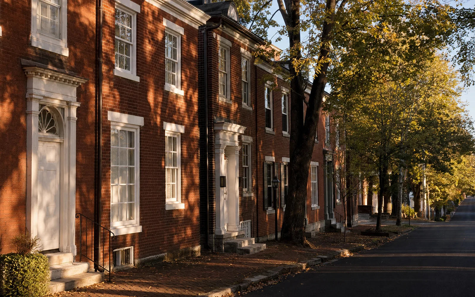 Row of Federal-style red brick townhouses with white-trimmed windows on a quiet historic street at golden hour, AI-generated illustration