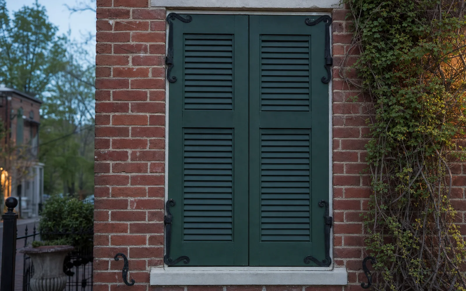 Closed green wooden shutters on a brick Federal-style building in soft evening light, AI-generated illustration