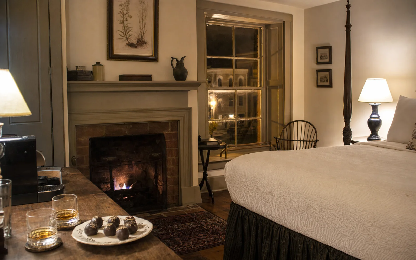 A cozy suite in a restored late-18th-century house with a lit gas fireplace, a made-up bed and a small plate of chocolate-covered candies, AI-generated illustration