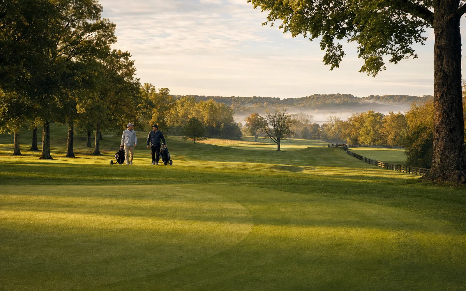 Contoured bentgrass green and a rolling fairway framed by old oaks in morning mist, with two golfers walking toward the green, AI-generated illustration