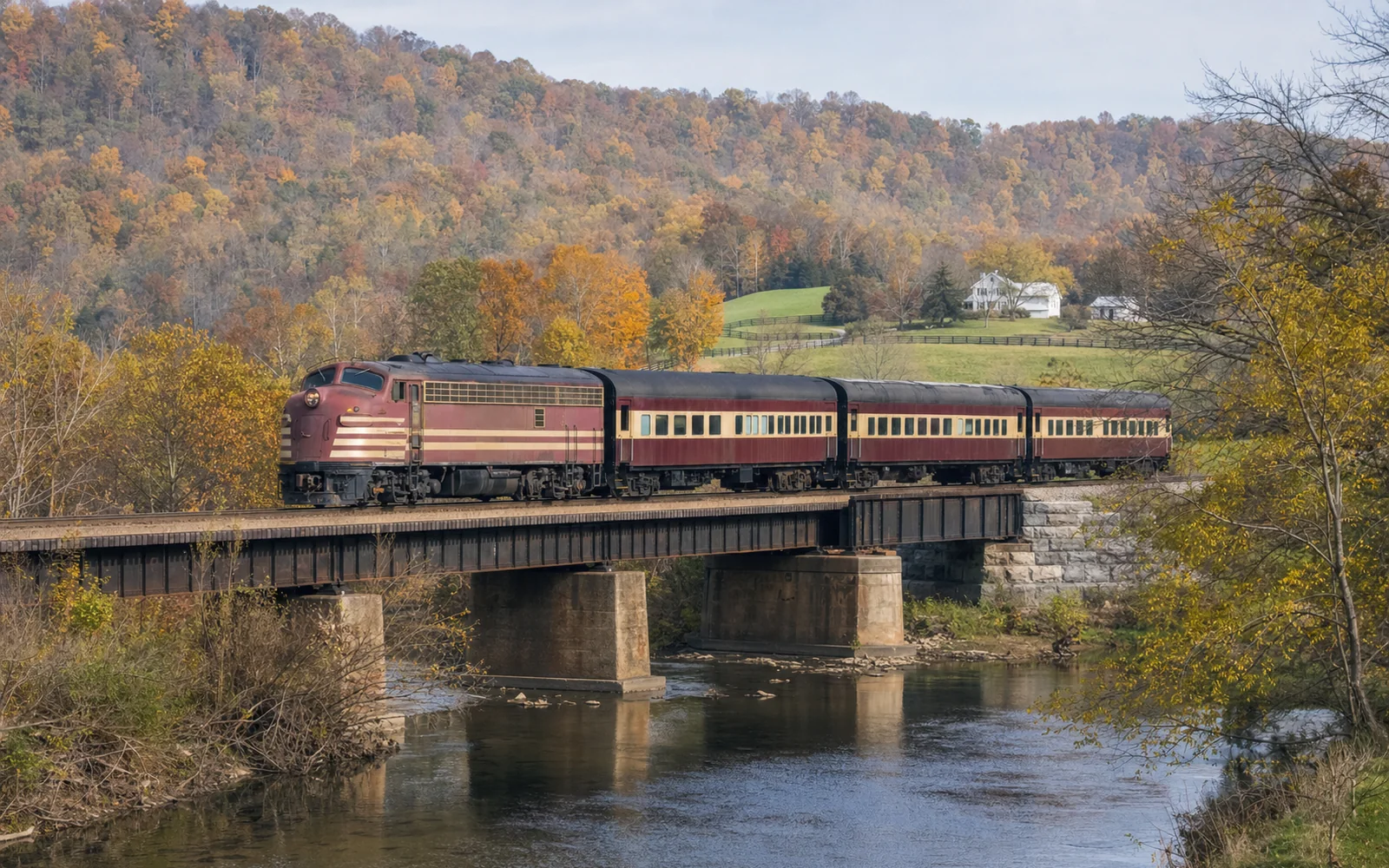 A vintage passenger train pulled by a maroon diesel locomotive crossing a small bridge through Kentucky farmland in fall color, AI-generated illustration